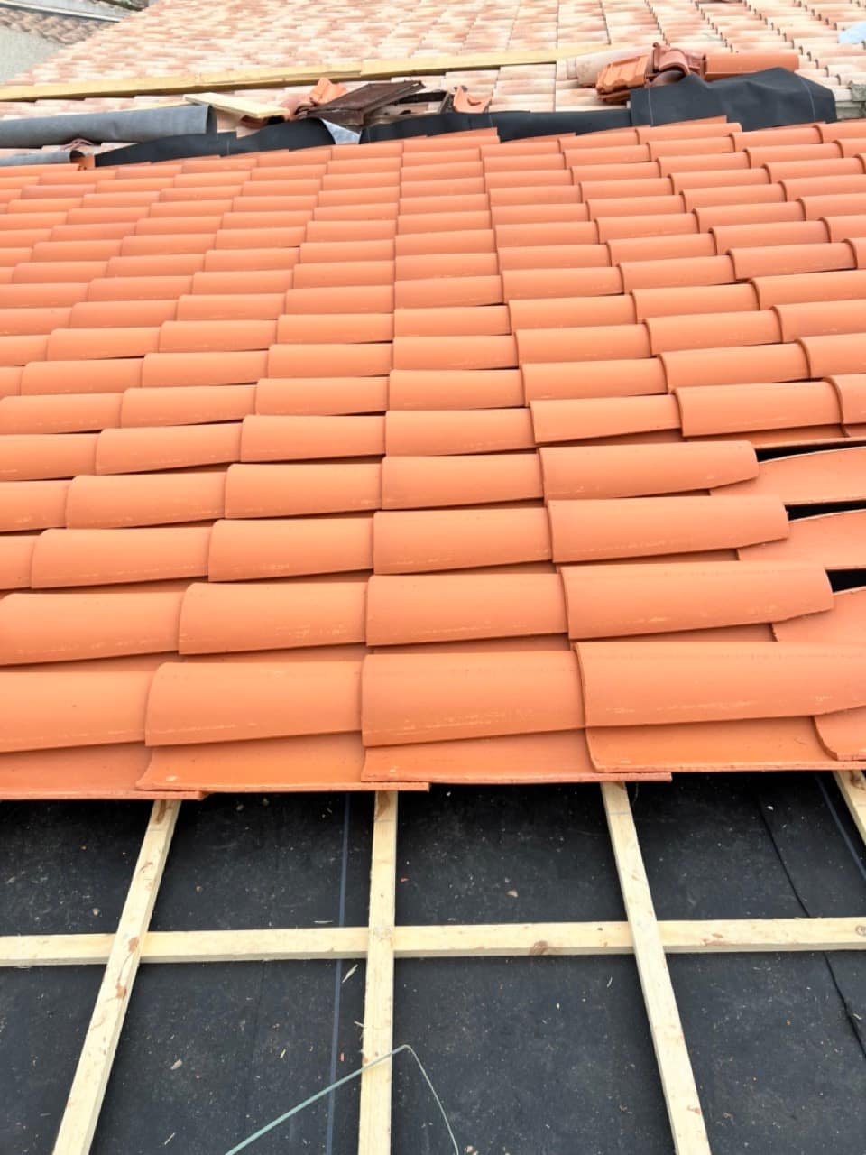 Tuiles neuves disposées sur un toit en cours de montage